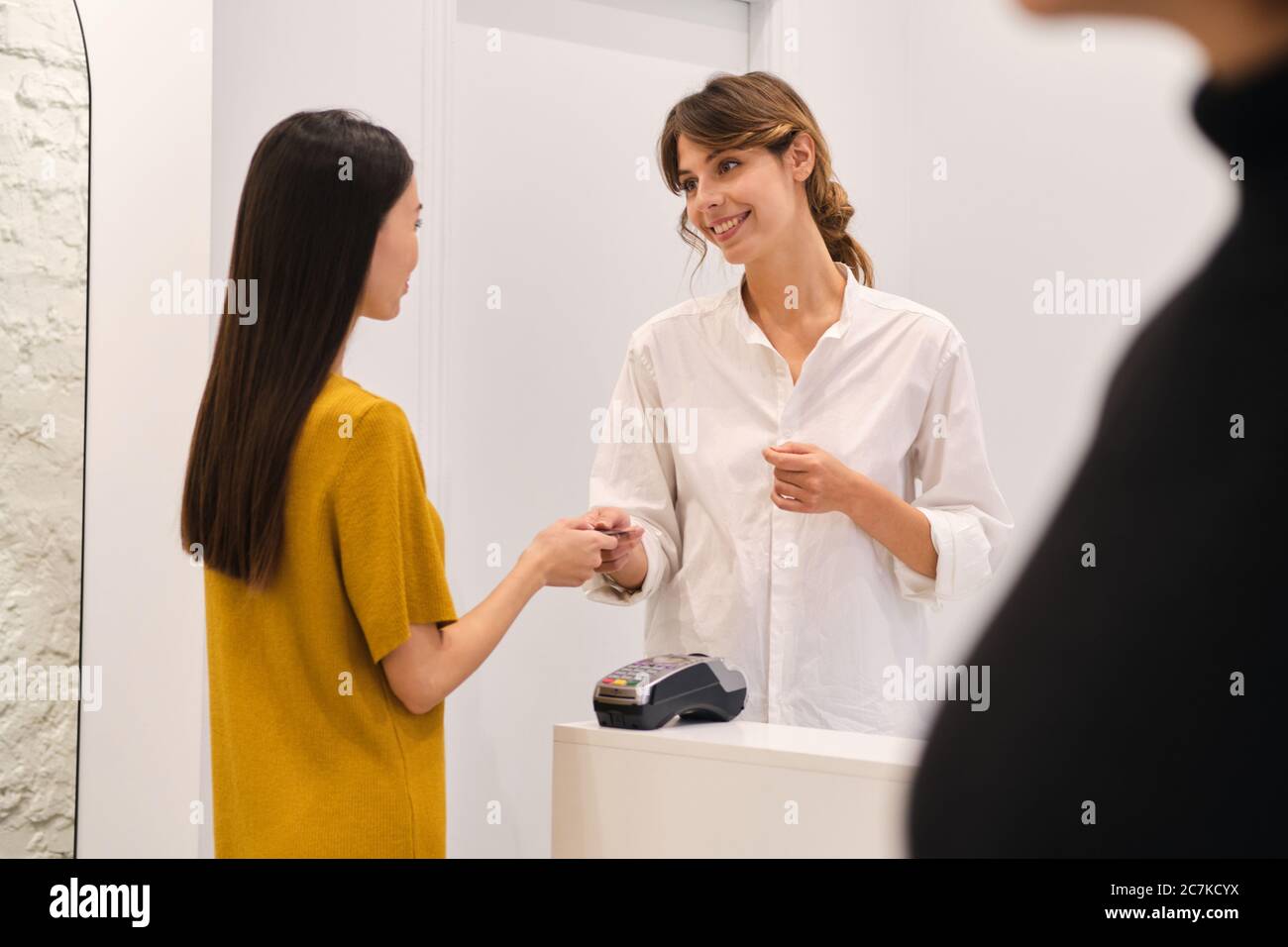 Giovane donna casual che paga con carta di credito in negozio di moda Foto Stock