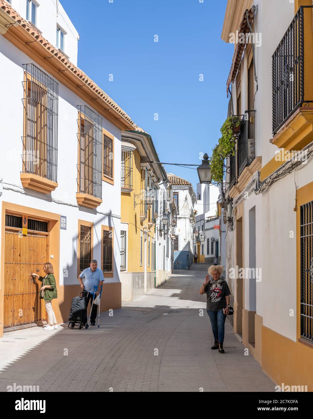 Bilanciere. Una donna in una t-shirt Rolling Stones cammina all'ombra lungo una colorata Calle Gutiérrez del los Ríos a Córdoba Foto Stock