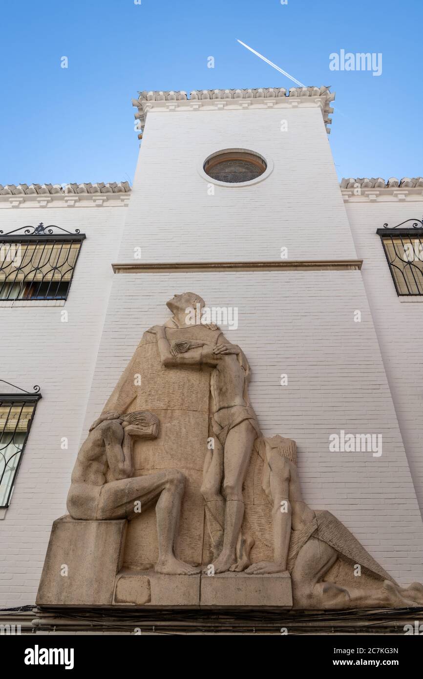 Una scultura di un monaco che guarda verso il cielo come un aereo vola sopra la residenza di San Juan de Dios per gli anziani nel quartiere Albaicin di Granada. Foto Stock