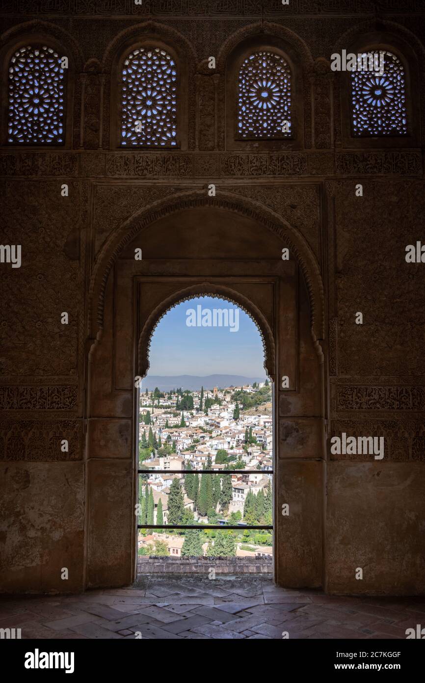 Gli edifici bianchi del quartiere moresco Albaicin di Granada attraverso un arco islamico ornato nel Mirador Nord del Giardino d'acqua Generalife Foto Stock