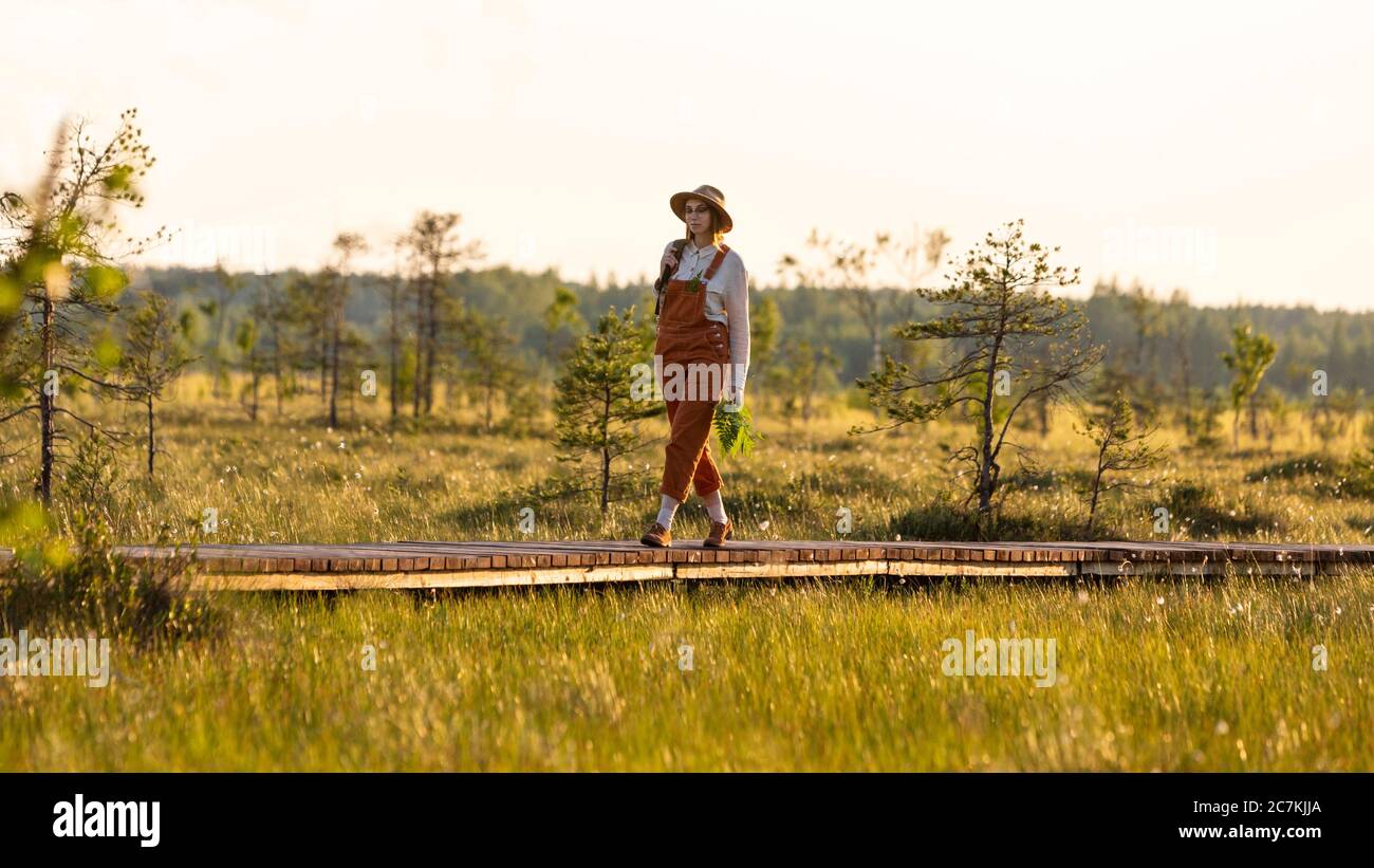 Donna botanica con zaino su sentiero escursionistico ecologico in estate all'aperto. Naturalista esplorare la fauna selvatica e avventura ecoturismo a piedi sul percorso Thr Foto Stock