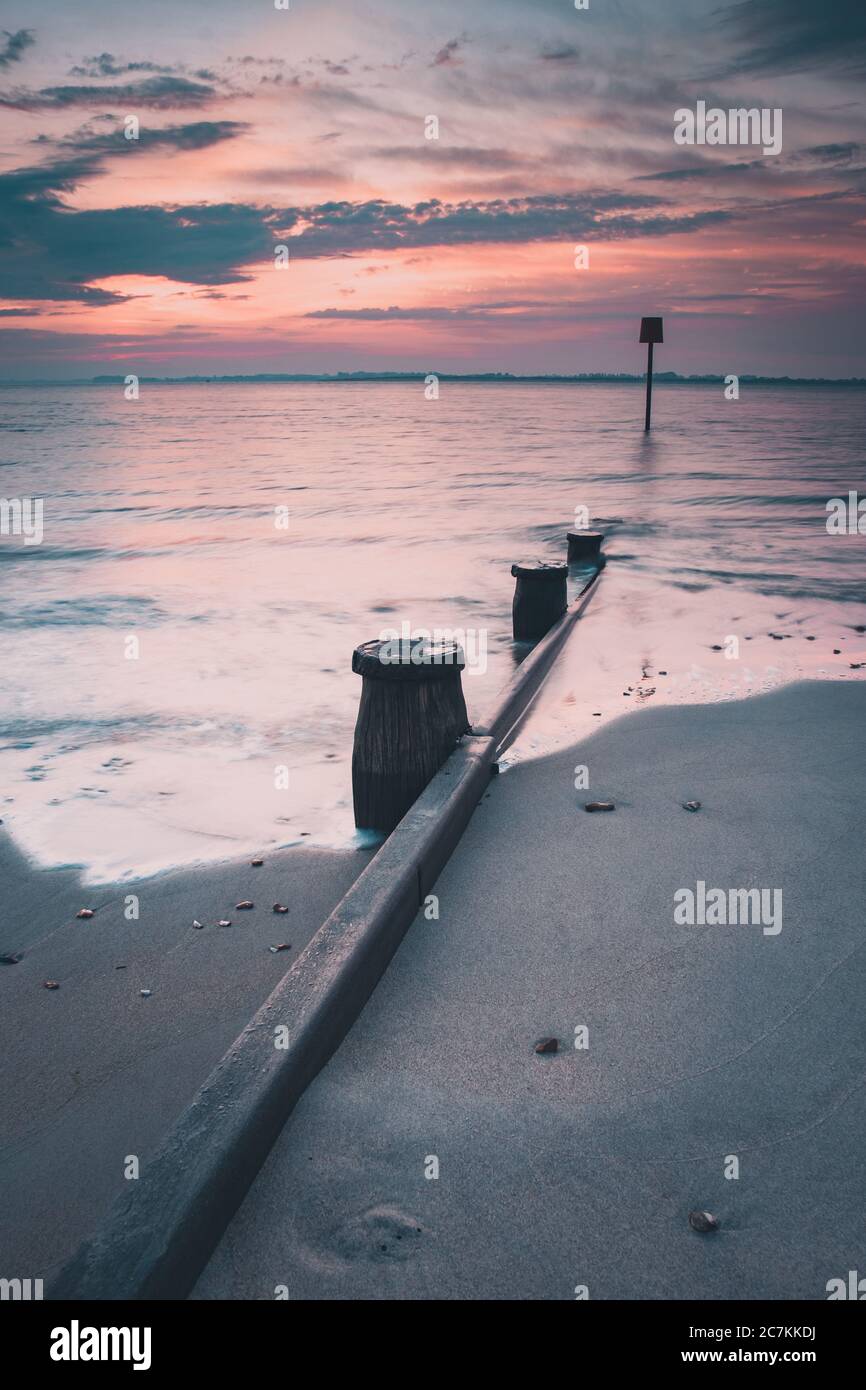 Un'alba tranquilla in una spiaggia di sabbia con una spiaggia di legno Groyne o marker, Hayling Island Beach, Hampshire, Regno Unito Foto Stock