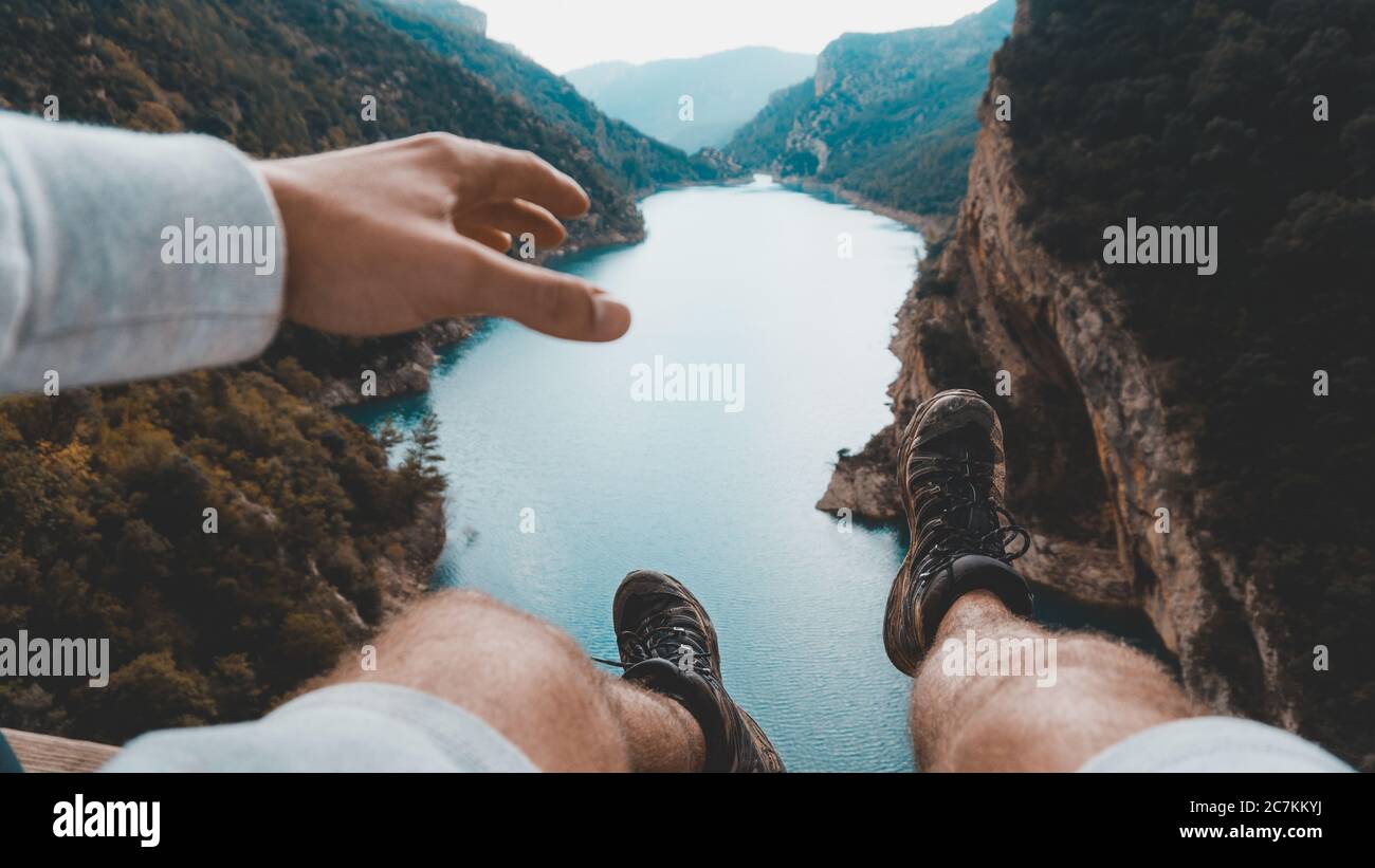 Bellissimo scatto di una persona sulla scogliera con un fiume limpido circondato da montagne Foto Stock
