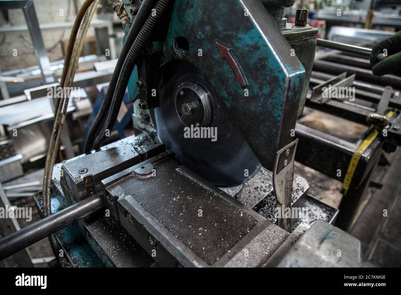 Primo piano di una vecchia macchina per il taglio di metalli in una fabbrica sotto le luci con uno sfondo sfocato Foto Stock
