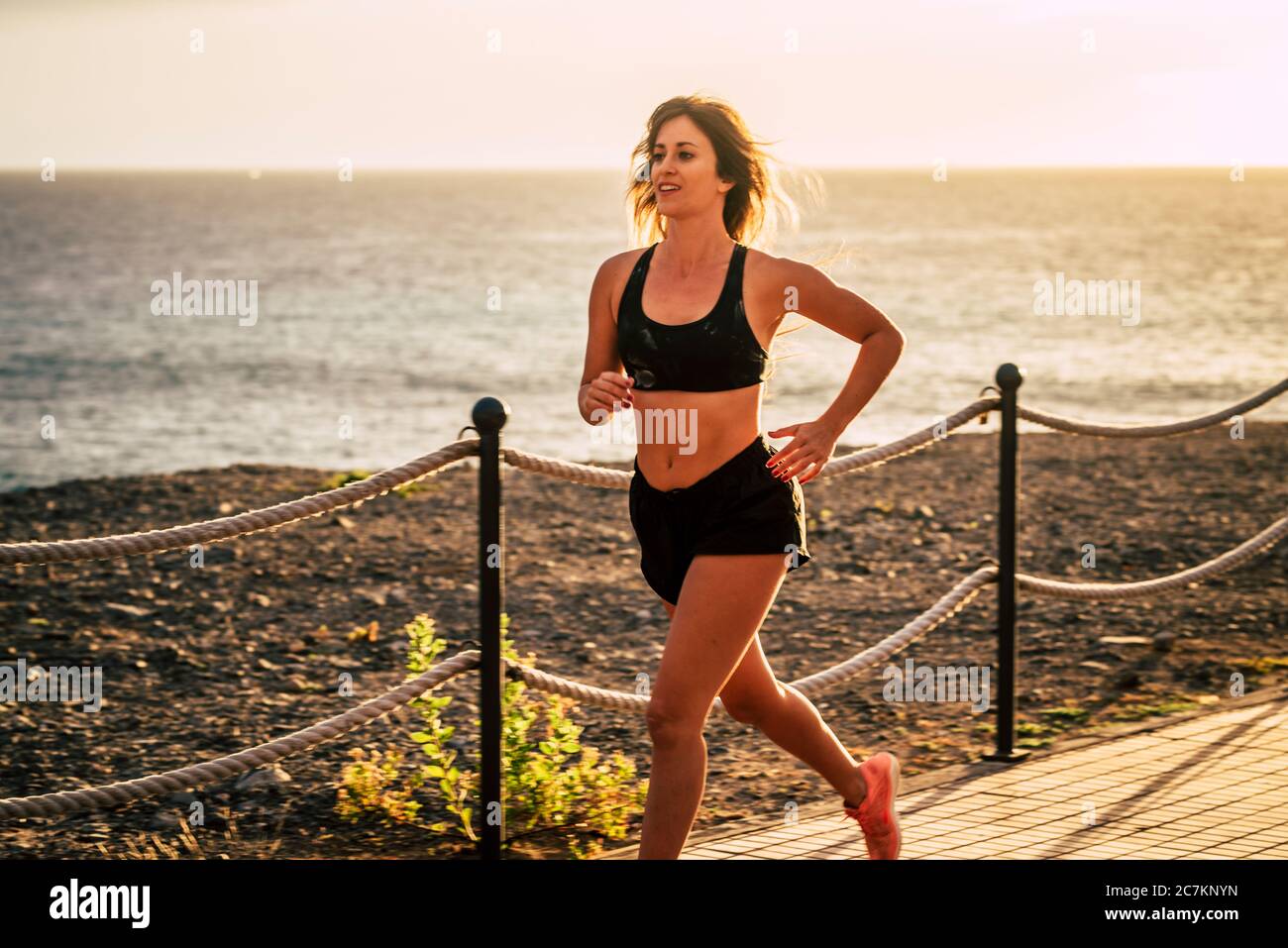 Felice e bella donna attiva persone in corsa attività di jogging all'aperto con vista oceano e tramonto sullo sfondo - sano stile di vita giovane caucasica femmina Foto Stock