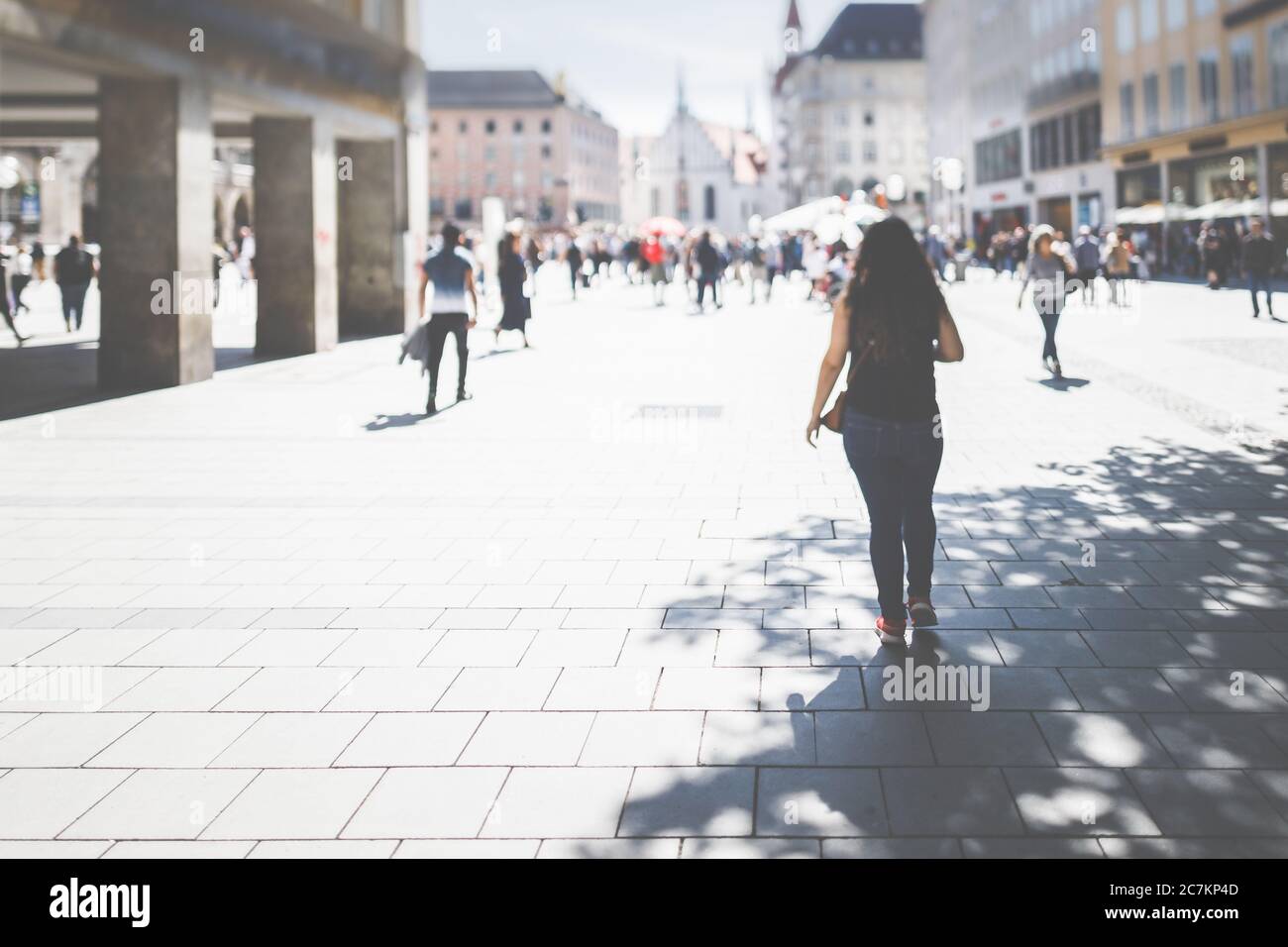 Vista posteriore di una donna nella zona pedonale di Monaco su Marienplatz. Shopping a distanza sociale, perso in città. Foto Stock