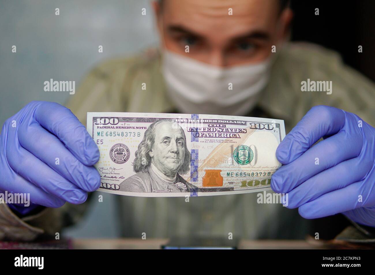 Le banconote americane da cento dollari sono conservate in guanti di gomma. Concetto di economia e minacce finanziarie durante la pandemia di Coronavirus. Guadagni in quarantena. Foto Stock