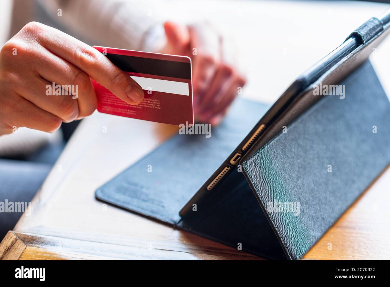 Primo piano le mani della donna che tengono una carta di credito e che utilizzano tablet per lo shopping online, e-banking. Foto Stock