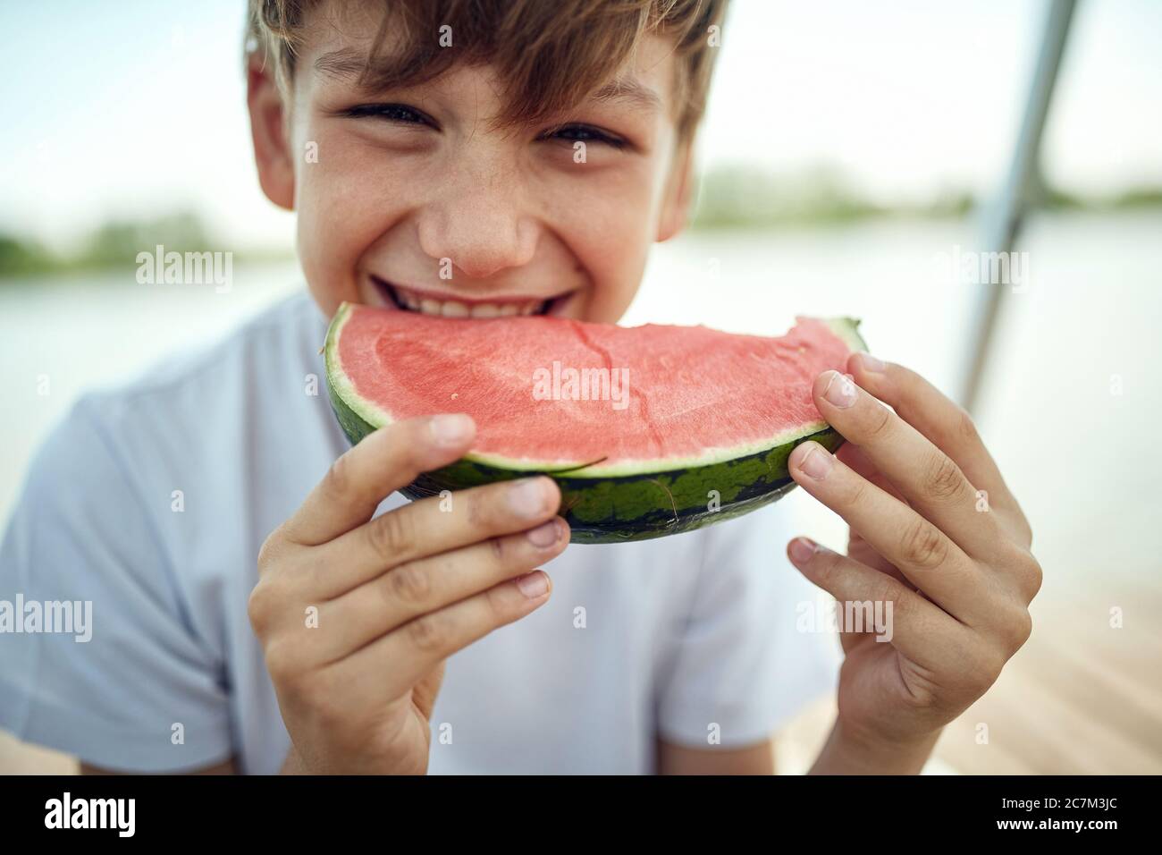 Ragazzo carino mangiare fresco cocomelon.Summer gioia dolce rosso cocomero. Foto Stock