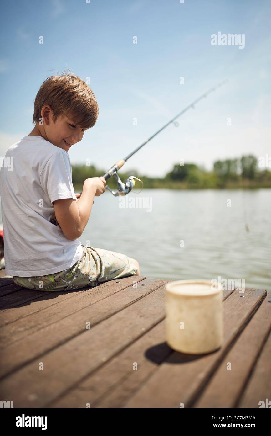 Buon ragazzo che si diverte in vacanza estiva e pesca in uno stagno. Foto Stock