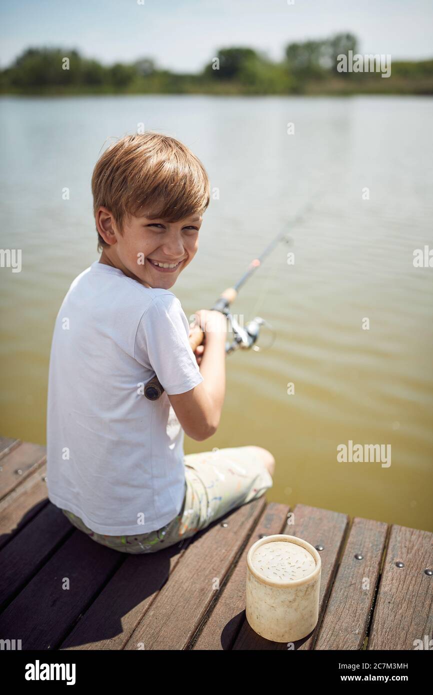 Ragazzo sorridente che si diverte a pescare in uno stagno.Estate gioia in vacanza. Foto Stock
