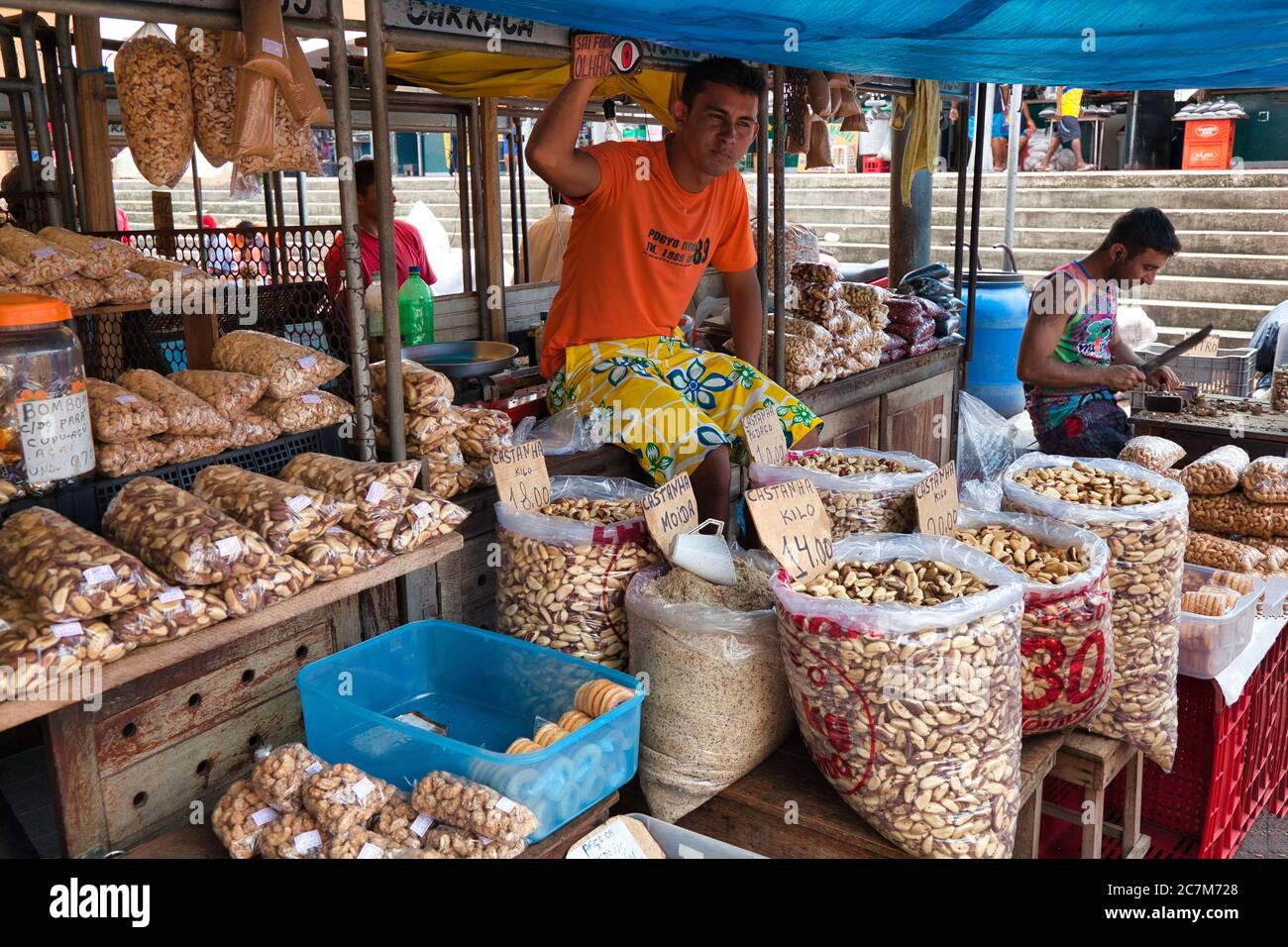 Un uomo al suo stallo di sacchi e sacchetti di noci brasiliane per la vendita nel mercato a Belem in Para Stato, Brasile. Foto Stock