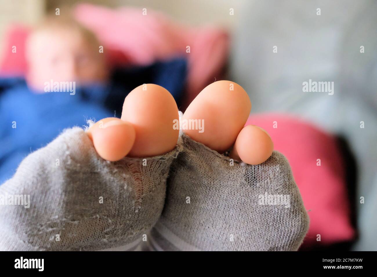 Primo piano di una persona che indossa una calza grigia strappata con uno sfondo sfocato Foto Stock