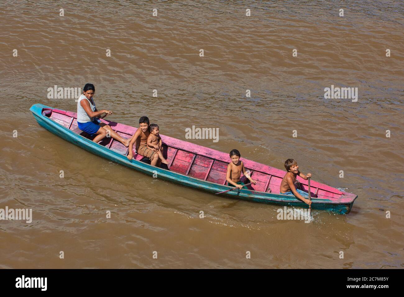 Una donna con quattro bambini in una canoa in legno sul fiume Amazzonia Foto Stock