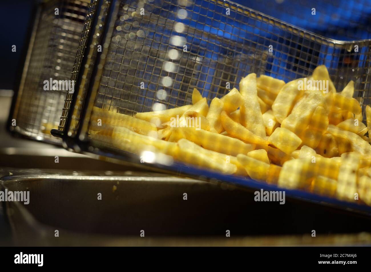 Primo piano di una deliziosa patatine fritte su un acciaio inossidabile friggitrice profonda in acciaio Foto Stock