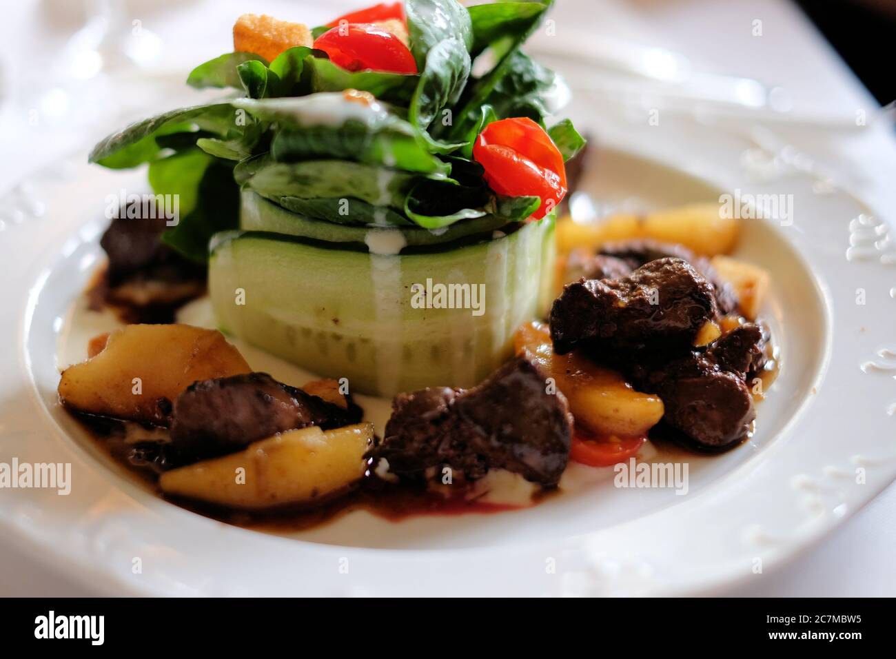 Primo piano di deliziosa carne con patate e foglie verdi verdure su un piatto bianco Foto Stock