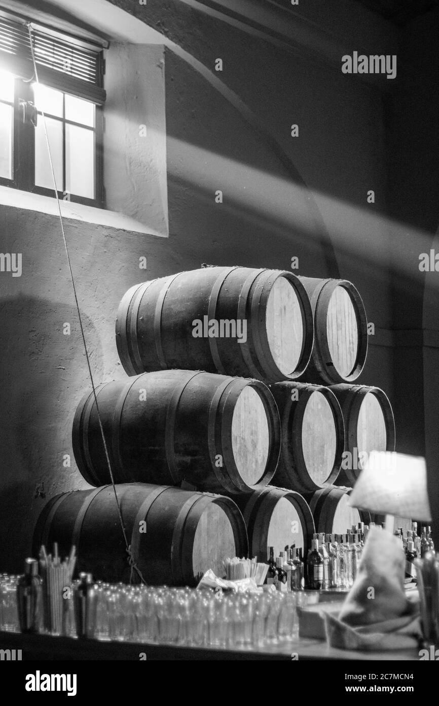 Scala di grigi di una pila di barili di legno con vetro bottiglie sulla superficie Foto Stock