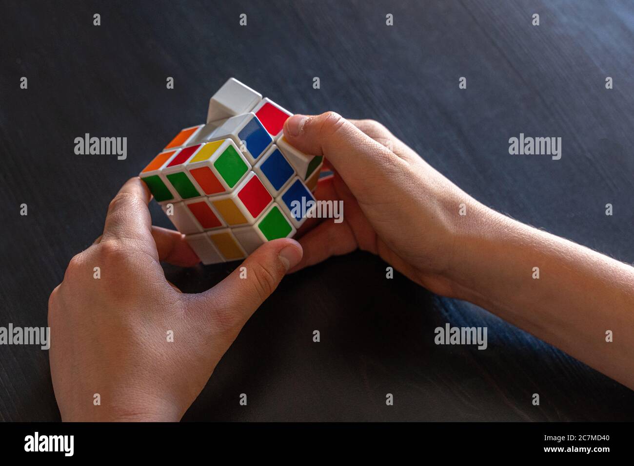 Le mani dei bambini cercano di risolvere il cubo di Rubik Foto Stock