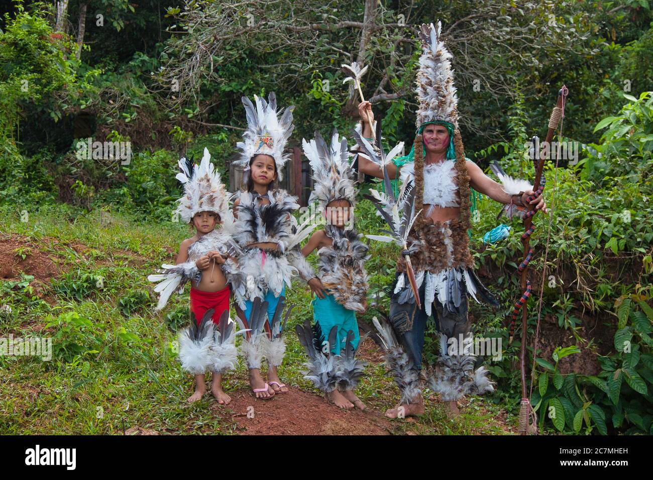 Un uomo e diversi bambini vestiti con abiti indiani brasiliani e piume nel villaggio di Boca De Valeria, Amazonas Stato, Brasile Foto Stock