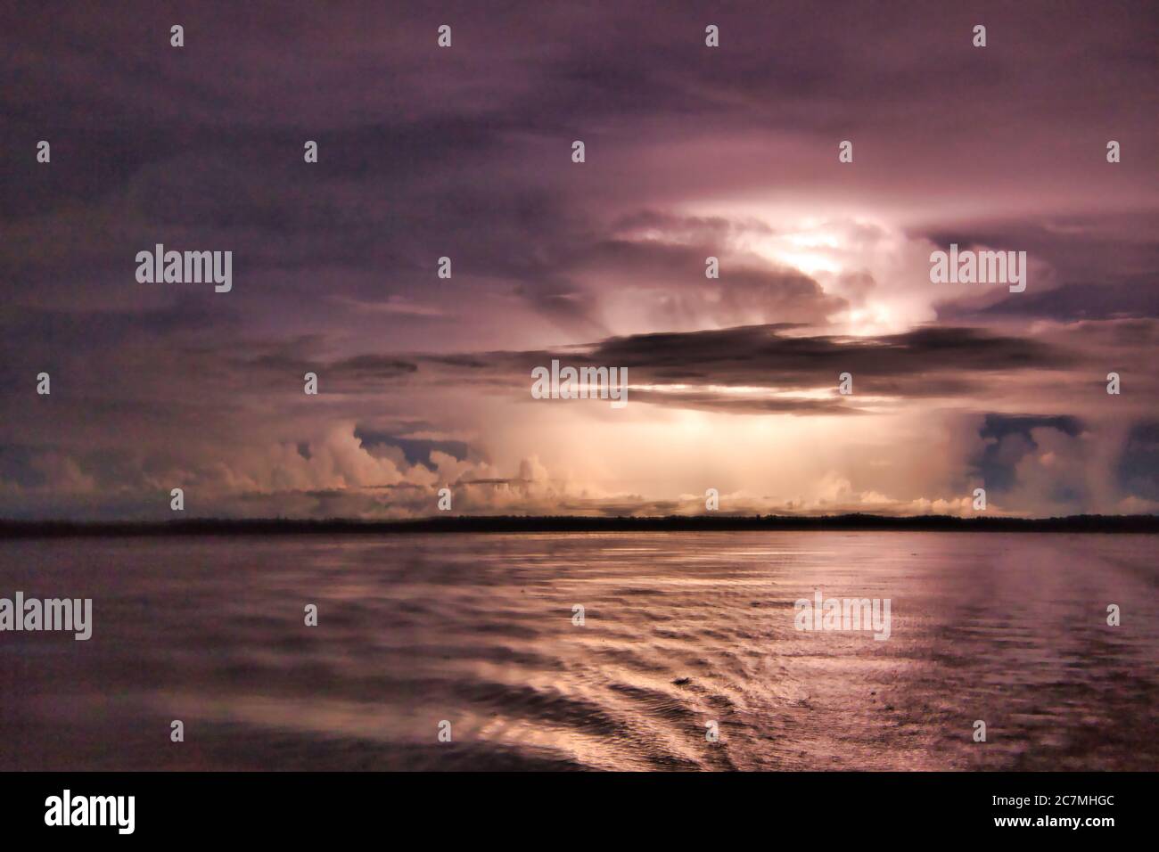 Sfreccia tra le nuvole di notte sul fiume Amazon che illumina le nuvole buie della tempesta dall'interno Foto Stock