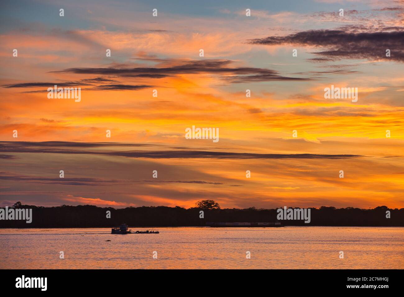 Alba sul fiume Amazzonia alle 6:00 con la riva del fiume lontano silhouette contro il drammatico rosso arancio e giallo alba cielo. Foto Stock