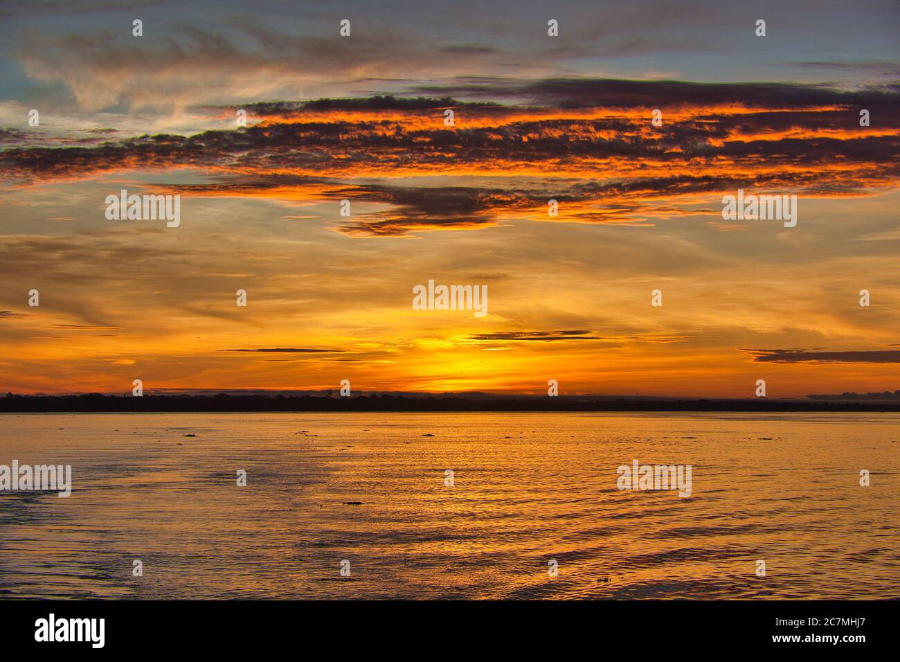 Alba sul fiume Amazon alle 6:00 con il suggestivo rosso arancio e giallo alba cielo mattina e la scia della nave in primo piano. Foto Stock