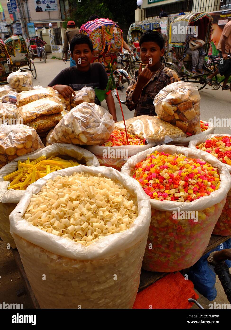 I venditori adolescenti mostrano i loro dolci nel mercato locale di Chittagong, Bangladesh. Questi dolci sono fatti di farina di grano e grammo, immersi nello zucchero e asciugati o fritti in olio e sono molto popolari tra i cittadini come spuntini. Foto Stock