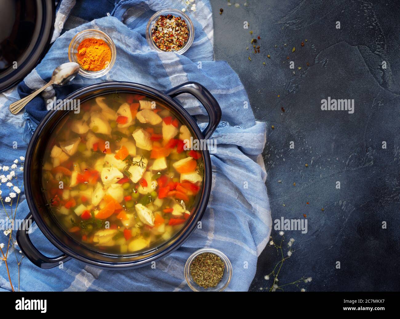 Ampia pentola blu con zuppa di pollo fatta in casa e spezie ciotole su sfondo blu Foto Stock