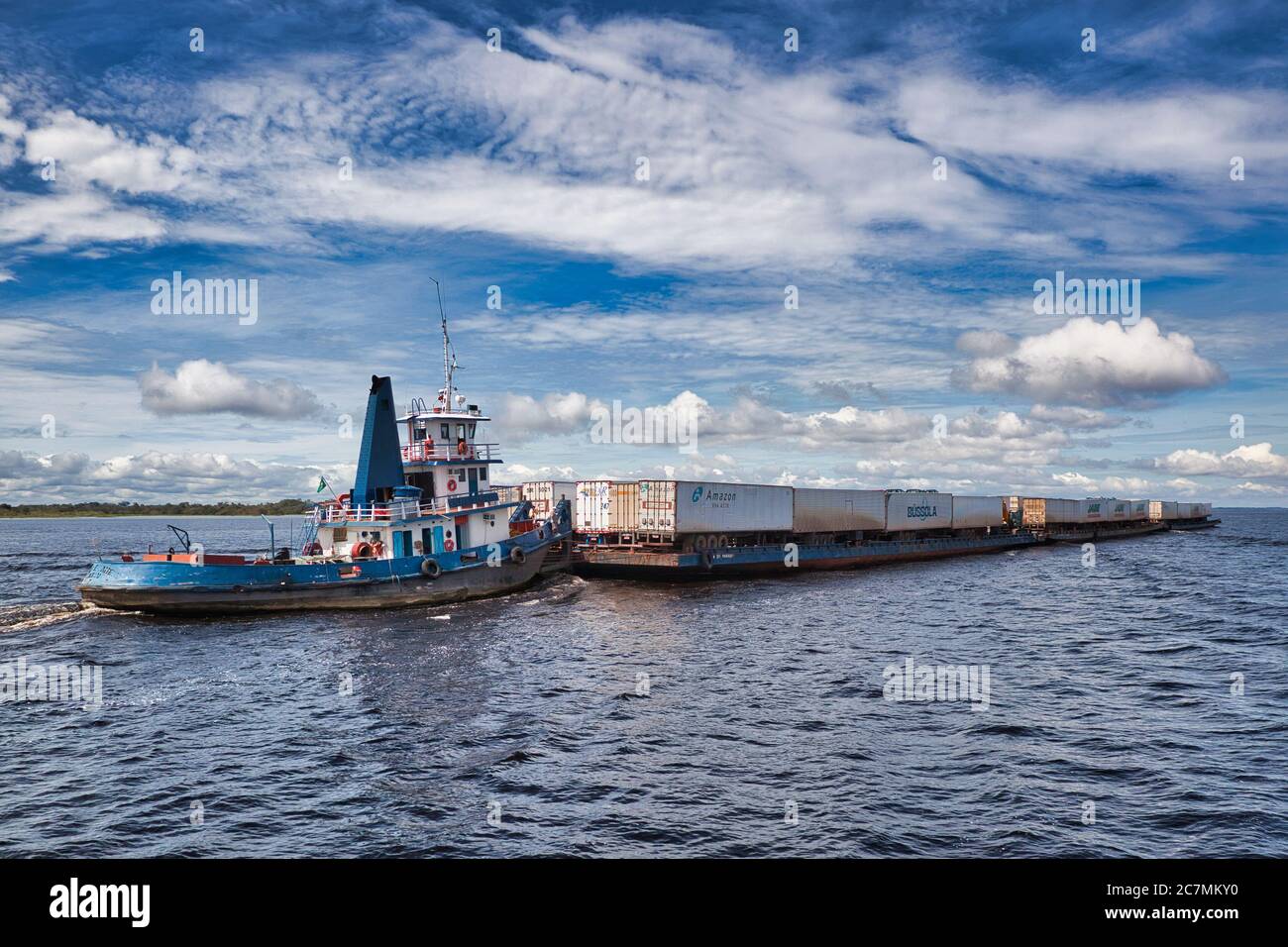 Una barca di rimorchiatore spinge tre grandi chiatte a monte verso Manaus sul fiume Amazon, chiatte completamente carichi di container di spedizione, Amazonas state, Brasile Foto Stock