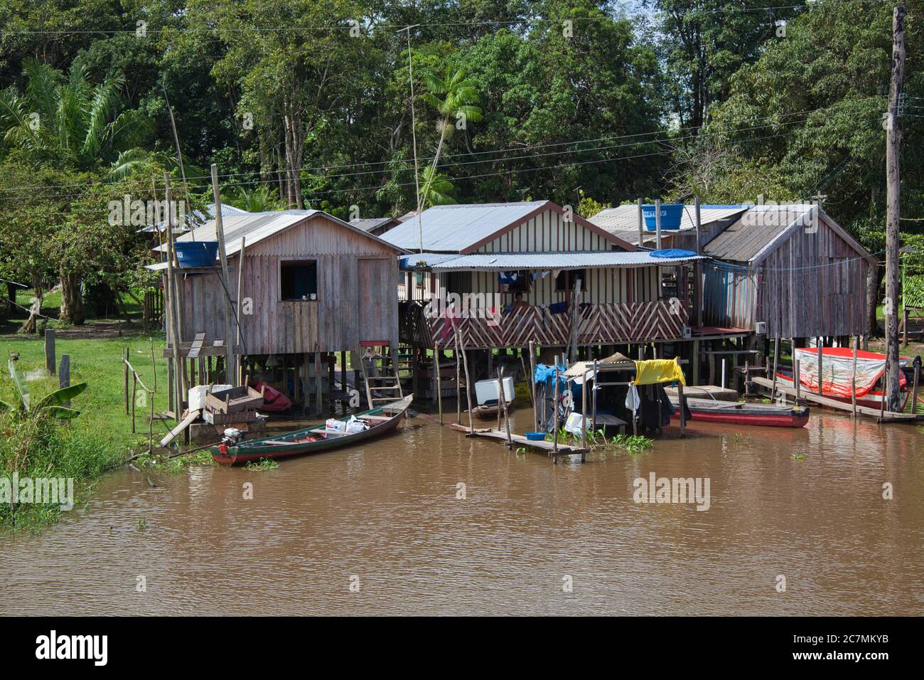Tre semplici case su palafitte con jetties per barche, sulle rive del fiume Amazzonia vicino Manaus, Amazonas state, Brasile Foto Stock