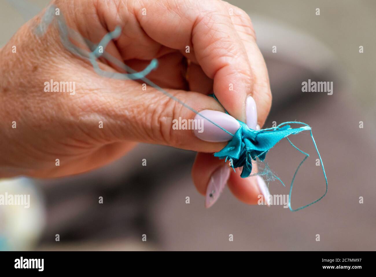 le vecchie mani femminili cucire il tessuto con un ago e filo Foto Stock