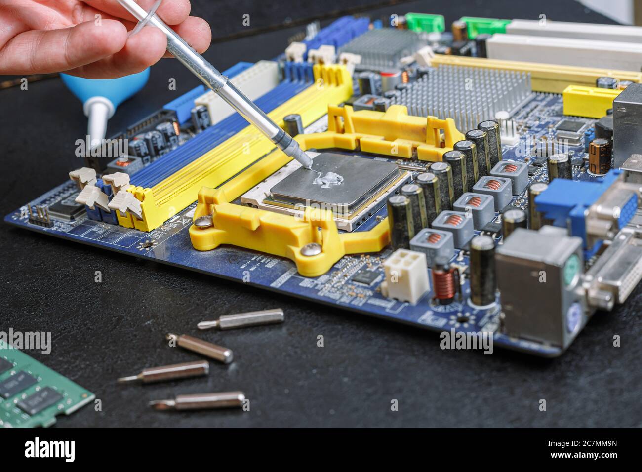 scheda madre del computer strizzare il grasso termico da una siringa, riparare l'apparecchiatura sul tavolo Foto Stock