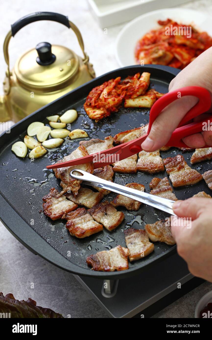 Samgineopsal cotto (grigliata pancia di maiale barbecue), tagliato con forbici Foto Stock