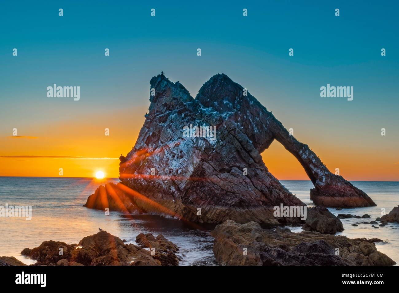 ARCO FIODLE ROCK PORTKNOCKIE MORAY COSTA SCOZIA ESTATE MATTINA ALBA NEL MESE DI LUGLIO CON IL SOLE CHE SORGE DAL MARE Foto Stock