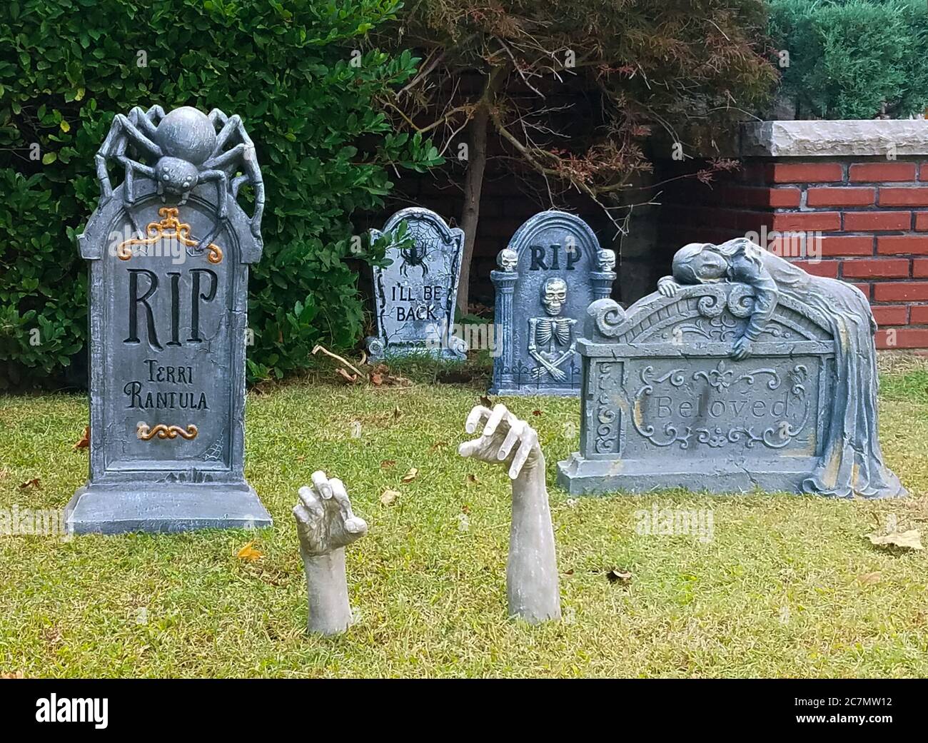 Decorazioni di Halloween di lapidi e mani che raggiungono fuori dal terreno di fronte a casa Foto Stock