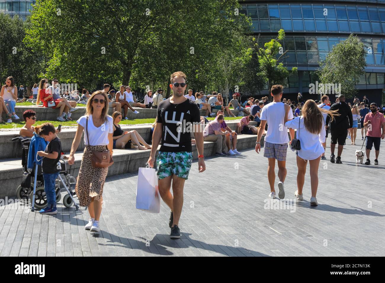 Londra, Regno Unito. 18 luglio 2020. Oggi, la gente cammina e si siede al sole nella zona intorno al municipio e al Potters Field Park. Il centro di Londra sembrava diventare più affollato oggi con più persone che lasciano le loro case per godersi il tempo soleggiato. Le regole di allontanamento sociale sembravano essere rispettate nella maggior parte dei luoghi, ma alcune aree sono già sempre affollate. Credit: Imageplotter/Alamy Live News Foto Stock