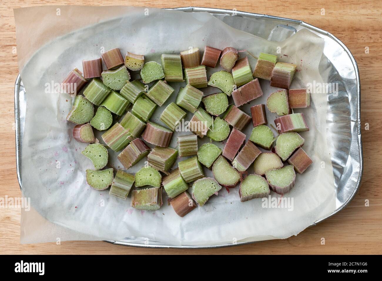 Pezzi di rabarbaro congelati in un unico strato su un vassoio Home congelare frutta estiva. Foto Stock