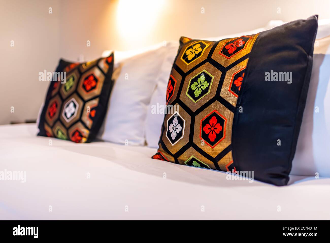 Camera moderna e contemporanea giapponese in stile ryokan con due colorati cuscini rossi verdi neri su un letto bianco pulito Foto Stock