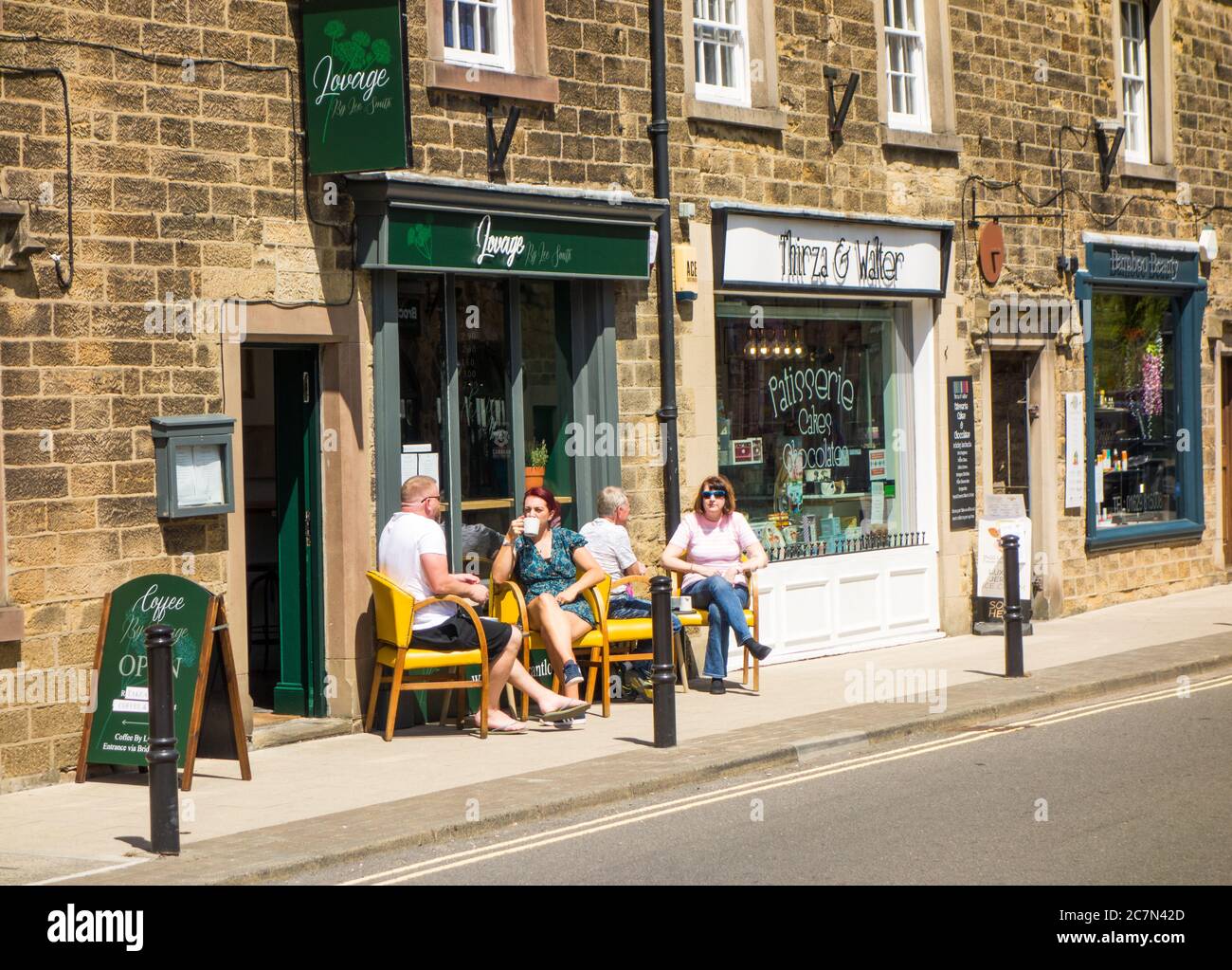 Turisti e visitatori che si recano in giornata seduti all'esterno in un caffè all'aperto nella cittadina di mercato del distretto di Derbyshire Peak di Bakewell, Inghilterra, Regno Unito Foto Stock