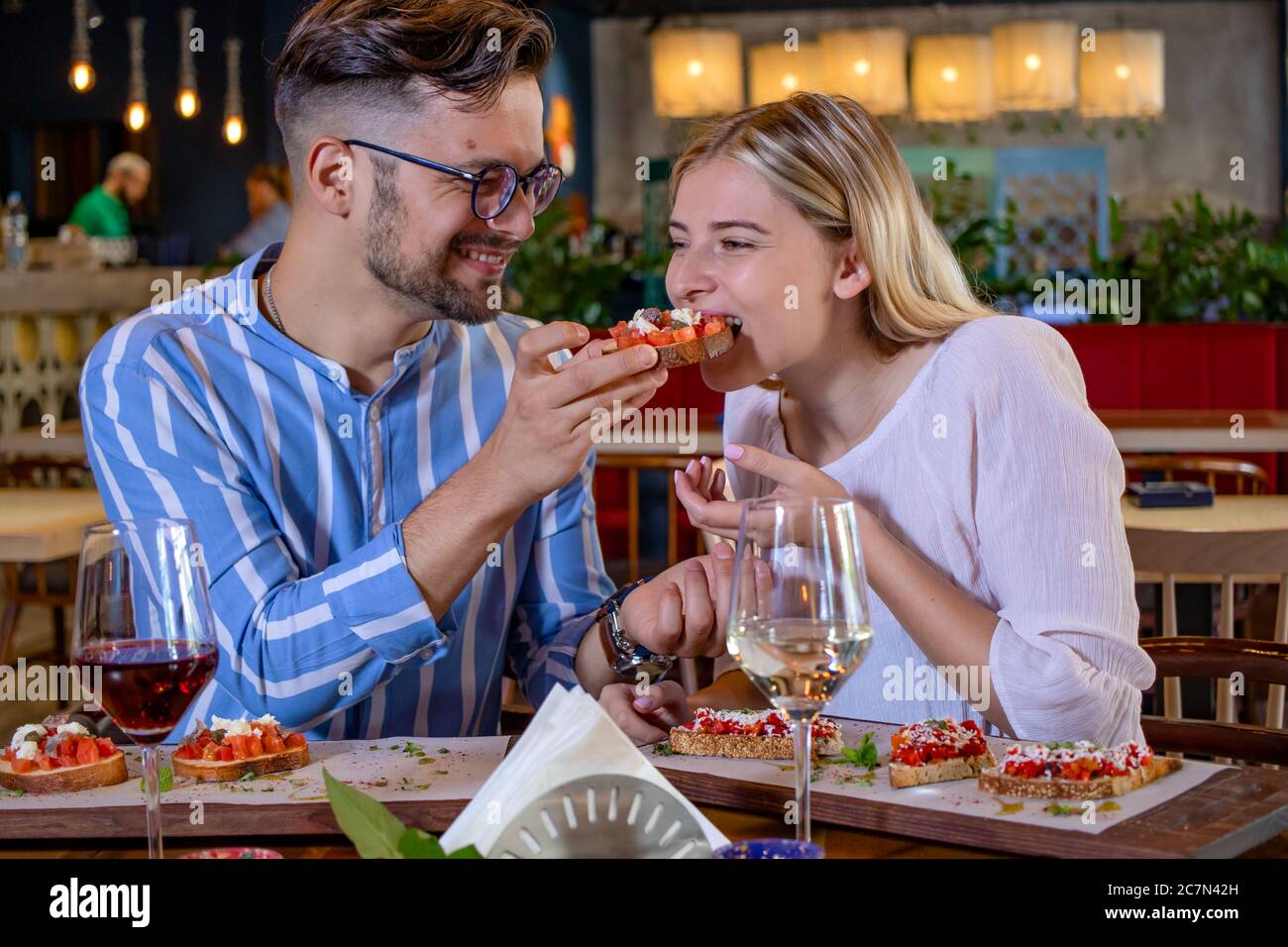 Felice giovane coppia romantica innamorata di nutrirsi con bruschetta a cena in un bel ristorante di fantasia. Foto Stock