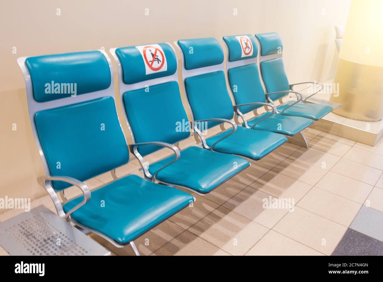 File di sedili color turchese nella sala d'attesa con un cartello applicato - non occupare, non sedersi. Concetto di distanza sociale, precauzioni pandemiche Foto Stock