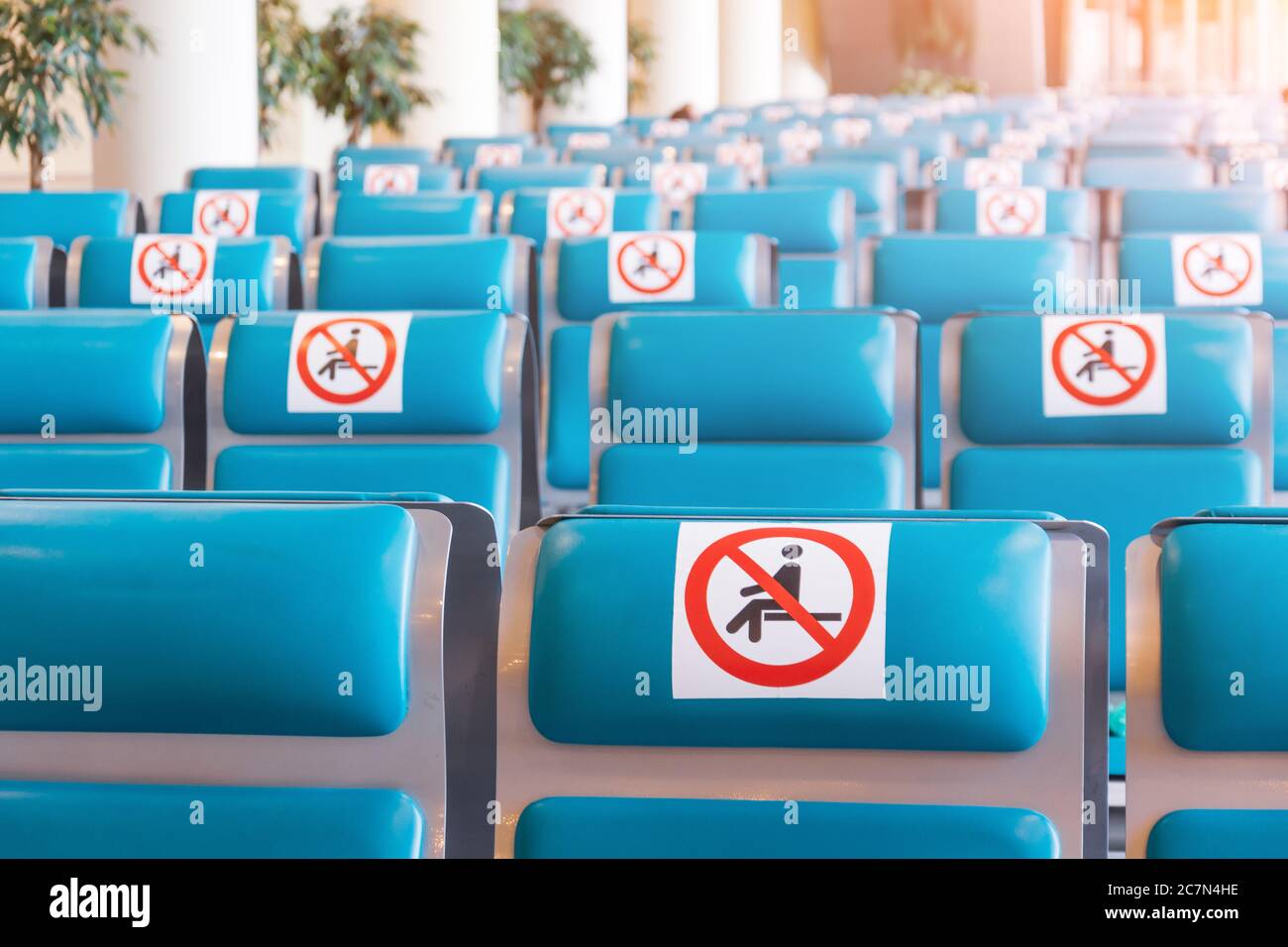 File di sedili color turchese nella sala d'attesa con un cartello applicato - non occupare, non sedersi. Concetto di distanza sociale, precauzioni pandemiche Foto Stock