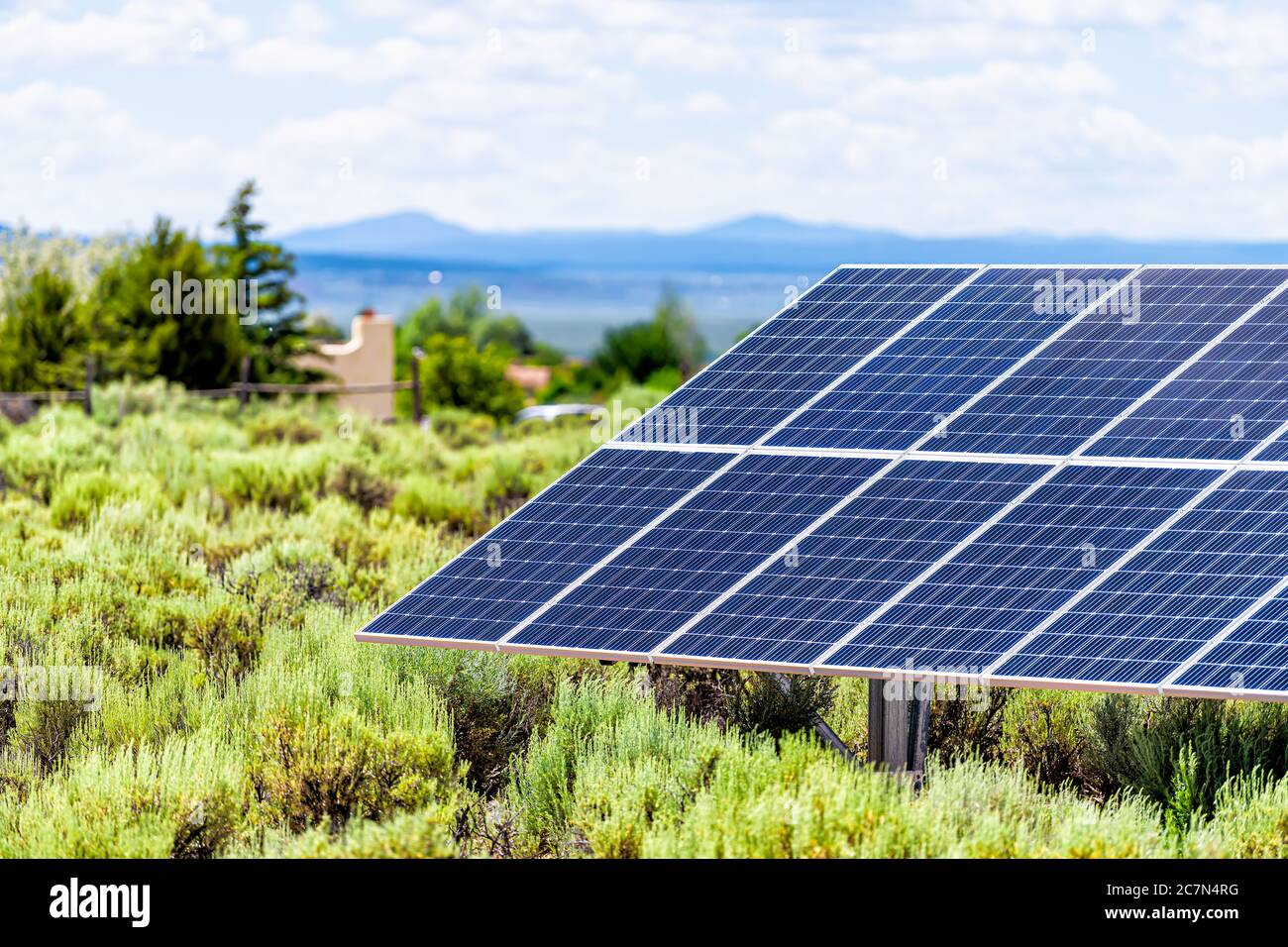 Valle Ranchos de Taos arbusti verdi paesaggio in estate e closeup di pannello solare durante il giorno di sole per casa fuori rete in New Mexico, Stati Uniti Foto Stock