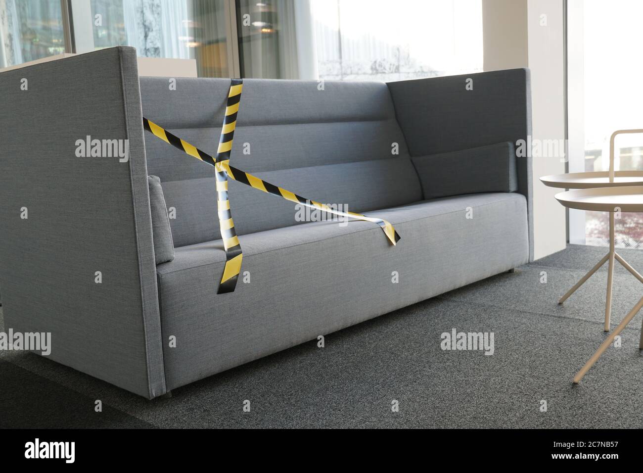 Regole di distanziamento sociale implementate in un edificio aziendale per fermare la diffusione del coronavirus e del covid-19. I divani nello spazio break sono parzialmente bloccati. Foto Stock