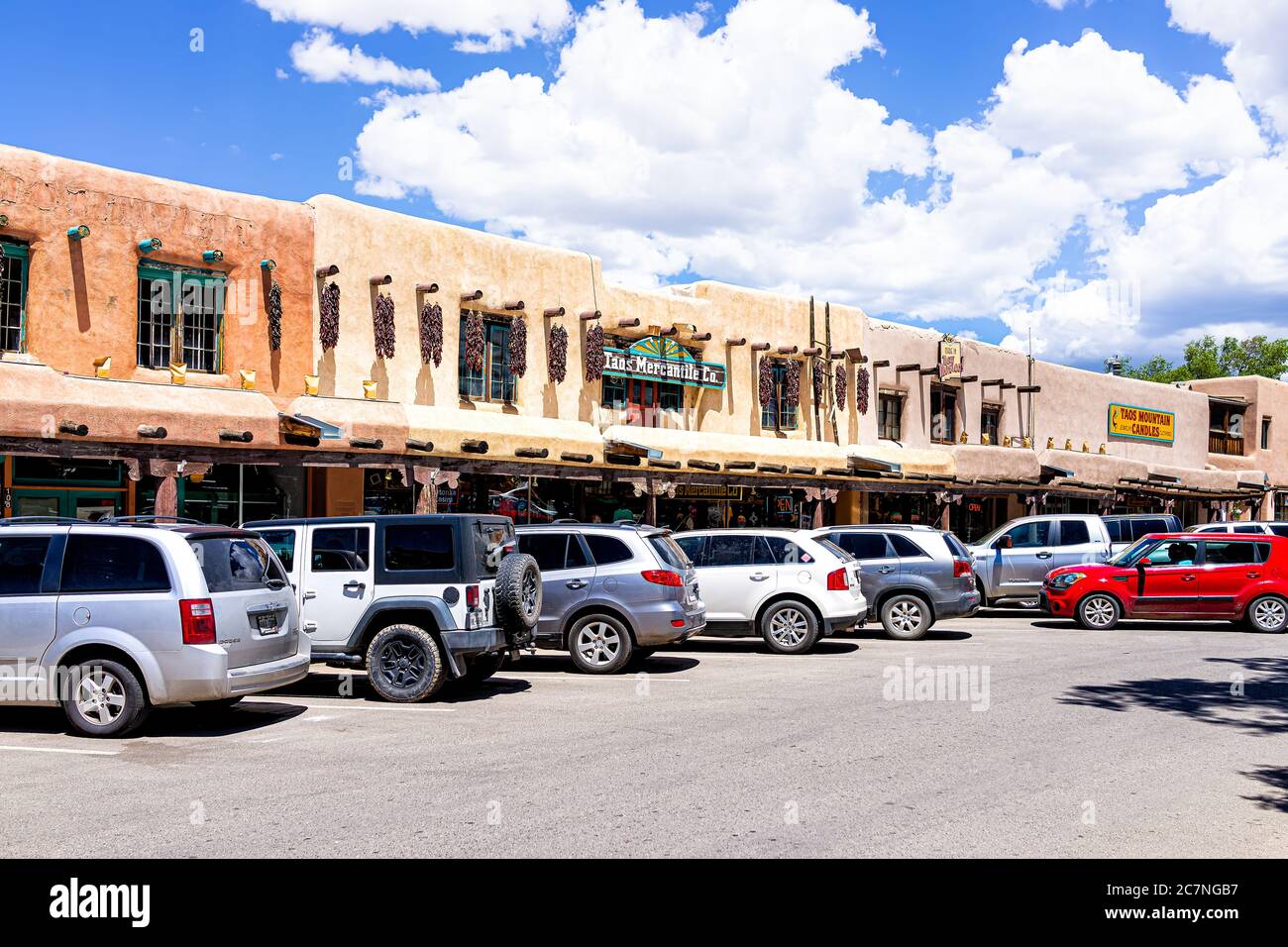 Taos, USA - 20 giugno 2019: Colorata piazza del centro di plaza nel famoso villaggio cittadino con cartello sul negozio esterno e auto parcheggiate in giornata di sole Foto Stock