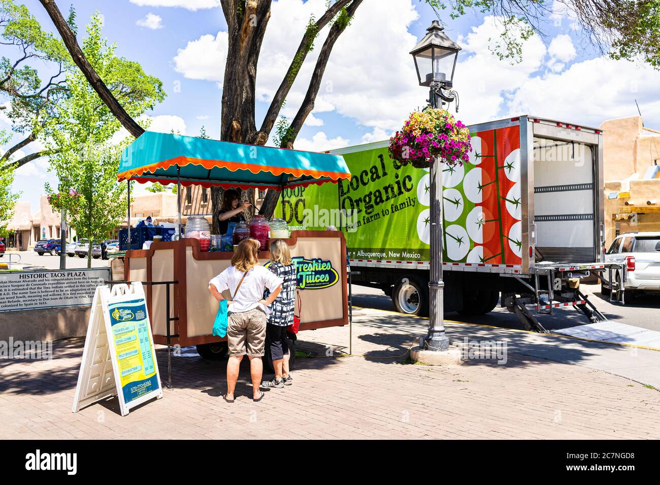 Taos, USA - 20 giugno 2019: Stand di cibo colorato nel centro di plaza piazza nel famoso villaggio della città con camion biologico e la gente che compra succhi Foto Stock