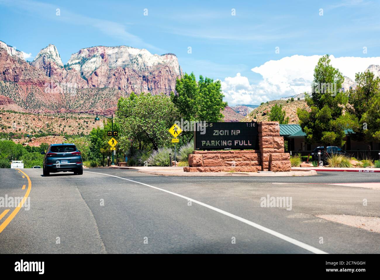 Springdale, USA - 5 agosto 2019: Cartello d'ingresso al Parco Nazionale di Zion con spazio per parcheggio completo sulla strada in Utah e auto nel punto di traffico stradale di vi Foto Stock