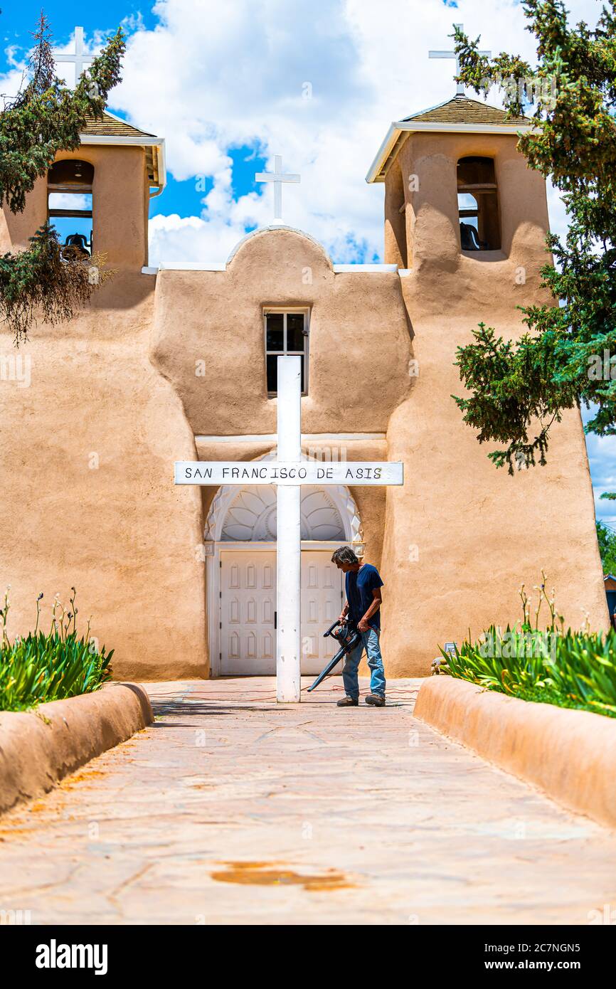 Ranchos de Taos, USA - 19 giugno 2019: Piazza San Francic e la chiesa di San Francisco de Aseis con la croce e l'uomo pulizia durante la costruzione in New Mexico Foto Stock