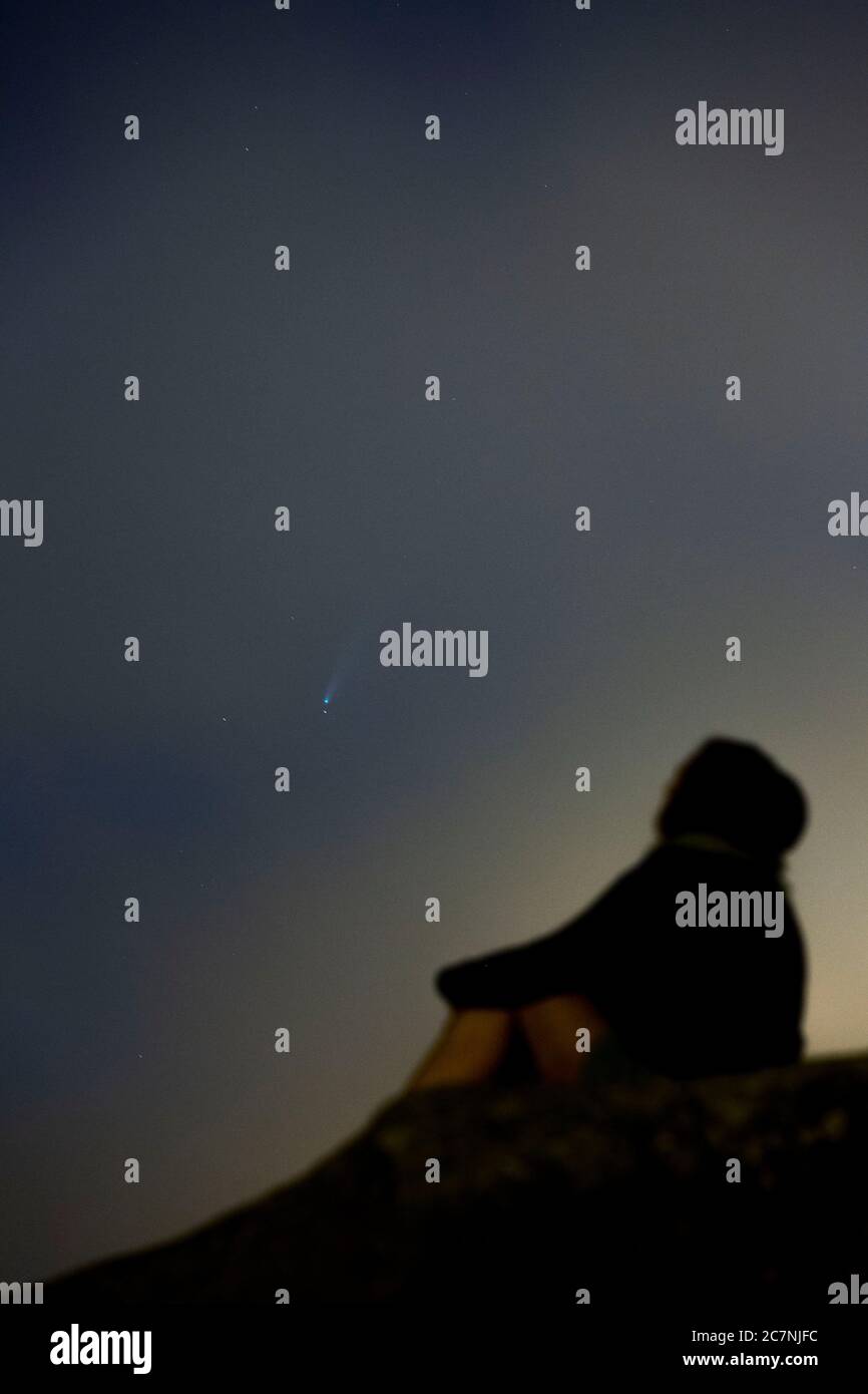 Una ragazza è vista guardare la Comet NEOWISE o C/2020 F3 dopo il tramonto con nuvole di fumo a causa dei forti incendi intorno alla città di Porto, Portogallo. Il 18 luglio 2020. La cometa è stata scoperta il 27 marzo 2020 da NEOWISE, il Near Earth Object Wide-Field Infrared Survey Explorer, che è un telescopio spaziale lanciato dalla NASA nel 2009. Foto Stock
