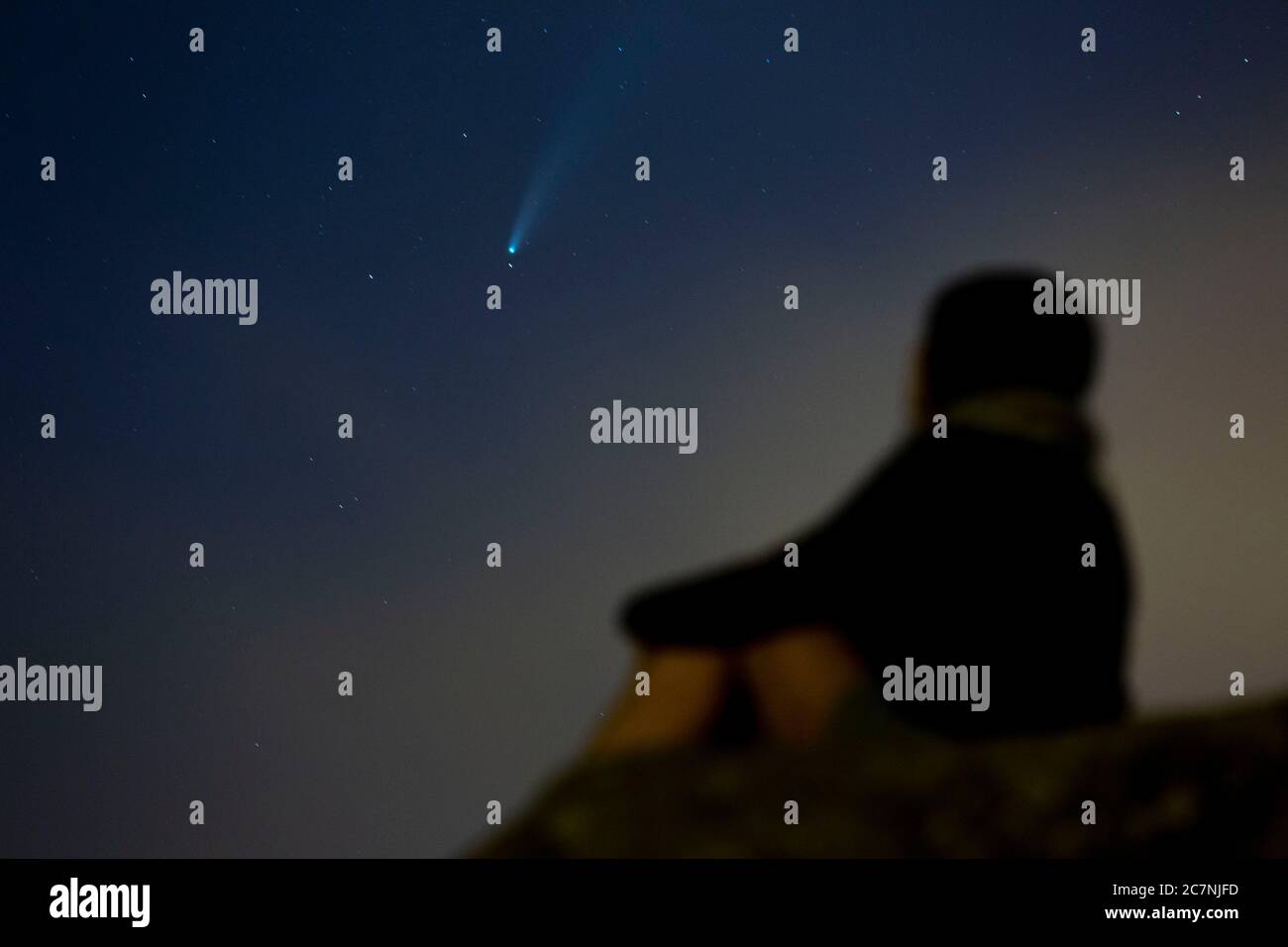 Una ragazza è vista guardare la Comet NEOWISE o C/2020 F3 dopo il tramonto con nuvole di fumo a causa dei forti incendi intorno alla città di Porto, Portogallo. Il 18 luglio 2020. La cometa è stata scoperta il 27 marzo 2020 da NEOWISE, il Near Earth Object Wide-Field Infrared Survey Explorer, che è un telescopio spaziale lanciato dalla NASA nel 2009. Foto Stock